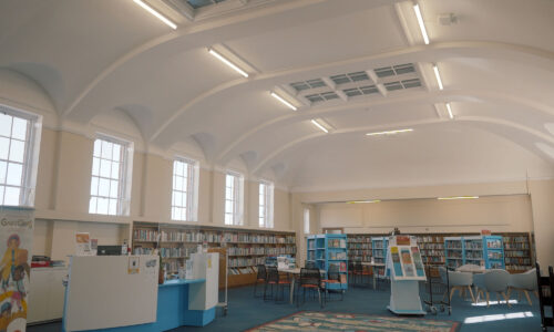 The inside of Cheriton Library, Folkstone. With a bright ceiling and led lighting strips along the ceiling.