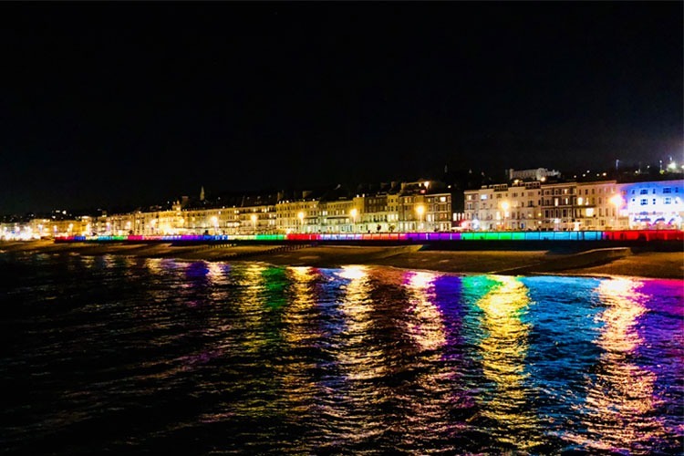 Bottle Alley Hastings at night time showcasing all the colours from the lighting - blue, red, green, purple - repeated along the strip.