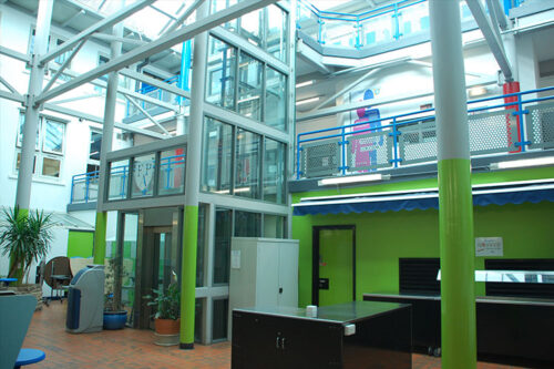 The inside entrance to Firth Academy in Sheffield, lots of metal beams and structures and the lower half is painted in a bright green.
