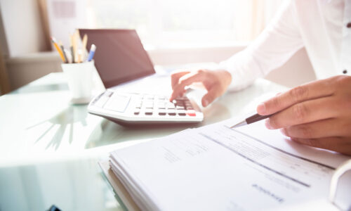 A white male's hands close up, hoovering over accounts and also using a calculator.