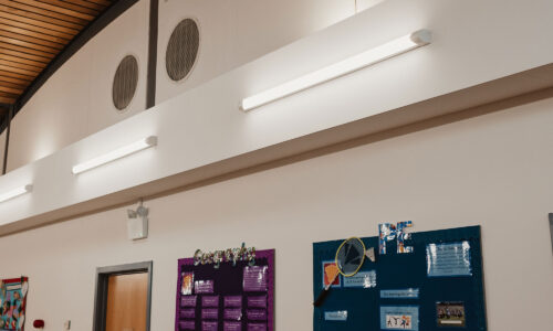 Inside school building showing bright white LED tube lighting on the white background walls. The room looks light and clear.